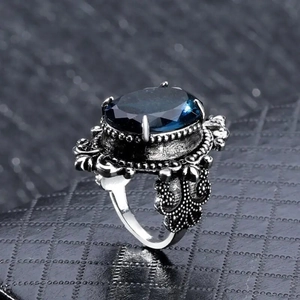 Dettaglio macro di un anello vintage reale con grande pietra blu e incisioni in argento antico