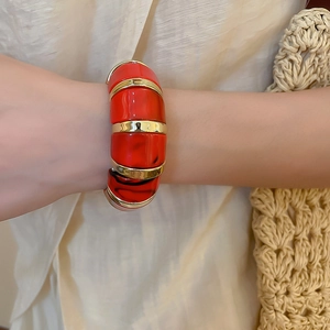 Detail of red marbled acrylic segments with gold metal spacers on a chic wrist cuff