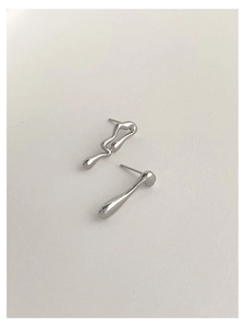 Macro shot of silver liquid metal style asymmetric earrings on a minimalist background