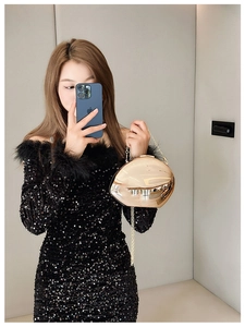 Detail of gold metallic mirror evening bag with delicate chain on sequin dress