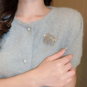 Exquisite gold hollow rose brooch with inlaid rhinestones on blue knit sweater detail