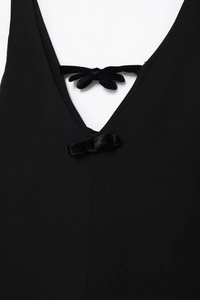 Détail d'une robe noire à col en V avec nœuds en velours et tissu tissé de qualité