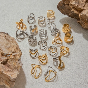 Mix of gold and silver titanium steel rings with textured finishes on sand background