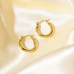 Dettaglio di orecchini a cerchio placcati in oro 18K con texture geometrica su seta