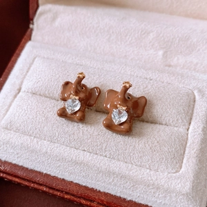 Macro detail of brown elephant stud earrings with heart crystal and gold accents