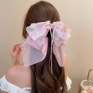 Dettaglio della pinza per capelli con fiocco in organza rosa, fiori e nastri sui capelli