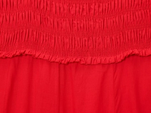 Close-up detail of red cotton midi dress featuring elastic smocked bodice texture