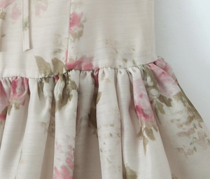 Dettaglio di un abito a fiori rosa con vita increspata e trama di seta lucida
