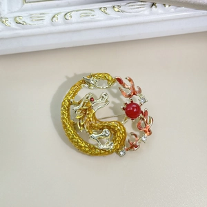 Detailed close-up of a gold dragon brooch with red pearl and sparkling crystal accents