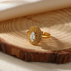 Close-up of golden marquise-cut crystal ring with textured finish on a rustic wood slice