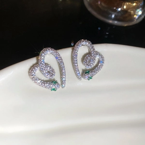 Macro view of heart-shaped snake earring with white zircons and green gemstone eyes