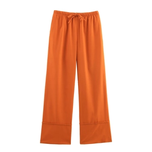 Close-up of orange linen wide-leg pants with drawstring waist and wide folded hem detail