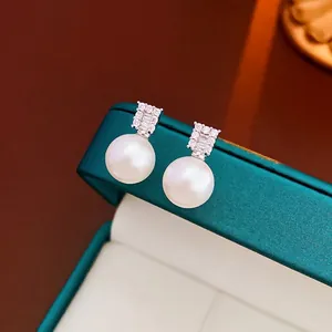 Elegant silver pearl earrings featuring rectangular zircon studs in a green jewelry box