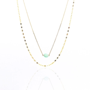 Close-up of double-layer gold necklace with light green gemstone on white background