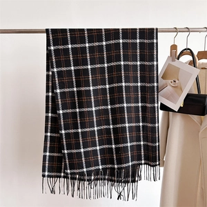Detail of soft black and brown plaid scarf featuring decorative tassels on a metal hanger