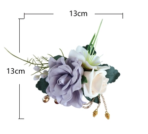 Détail d'un corsage de roses artificielles lavande et blanches avec chaîne dorée chic
