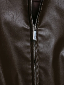 Detailed macro view of dark brown faux leather texture and silver metal zipper on jacket