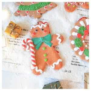 Detail of gingerbread man and Christmas tree clay ornaments on festive snowy background