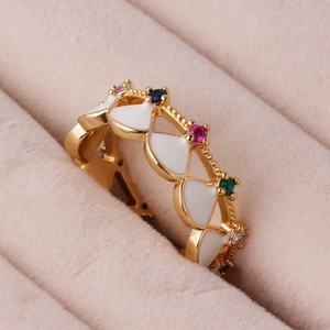 Macro shot of gold plated geometric ring with colorful gems and white enamel petals