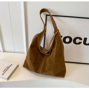 Close-up of brown faux suede Hobo tote bag with stylish strap on a minimalist set