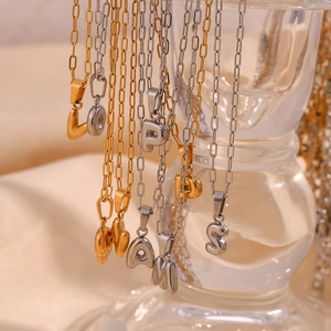 Macro shot of gold and silver paperclip chain necklaces with bubble letter pendants