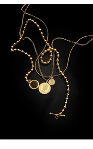 Close-up of a three-layer gold coin necklace with snake chains and an OT toggle clasp