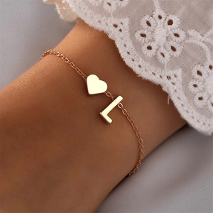 Detailed macro view of a gold heart charm and letter L pendant on a delicate chain