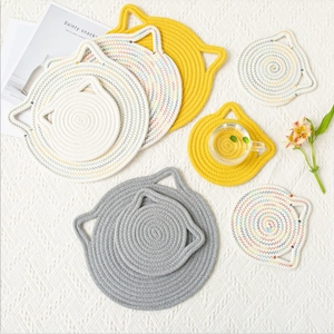 Cat-shaped cotton woven placemats and coasters set in multiple colors on a textured cloth