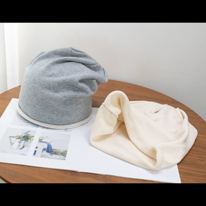 Minimalist knit slouchy beanie hats in grey and off-white colors on a wooden table