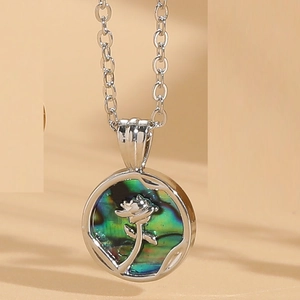 Detail of flower pattern on abalone shell pendant with silver metal chain