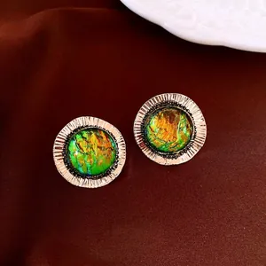 Vintage round gold earrings with colorful resin inlay on luxury brown velvet surface