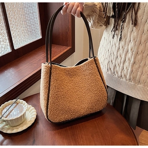 Close-up of brown faux shearling tote bag texture with dark leather handle detail