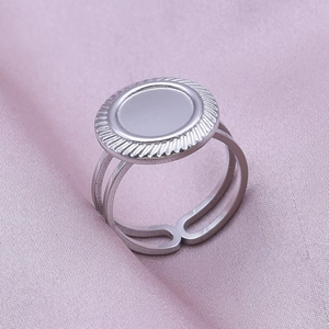 Macro view of adjustable stainless steel ring with white shell inlay on purple silk fabric