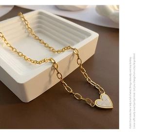 Detail of golden heart pendant necklace with oval link chain on elegant display stand