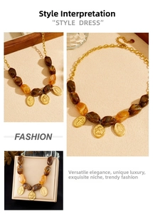 Close-up of retro gold necklace featuring amber marble beads and engraved coin pendants