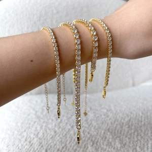 Detail of four gold-plated tennis bracelets with clear cubic zirconia on a model's arm
