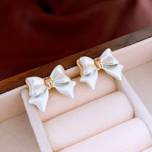 Macro shot of pearl white bow stud earrings on a velvet jewelry display tray