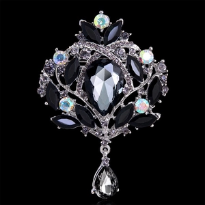 Macro detail of vintage alloy brooch with grey pear-shaped gem and multicolored rhinestones