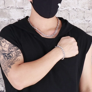 Gros plan sur l'ensemble collier et bracelet Figaro en acier argenté pour homme chic