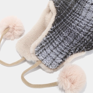 Close-up of soft plush faux fur texture and pink pom-poms on the winter earflap hat