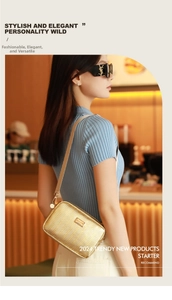 Close-up of golden cross-body camera bag with V-shaped quilting and metal plate detail