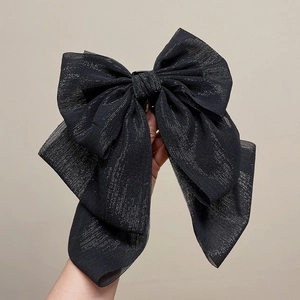 Détail d'une grande pince à cheveux nœud noir avec une texture en tissu scintillant