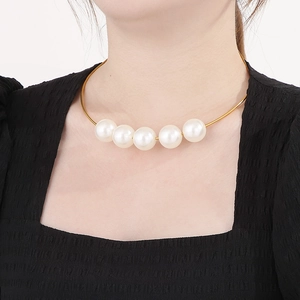 Close-up of a gold metal choker necklace with five large white pearls on a model neck