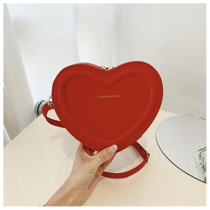 Dettaglio della borsa a tracolla rossa a forma di cuore con logo dorato inciso
