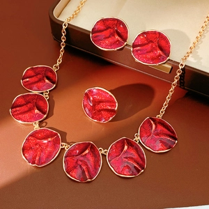 Detailed view of red enamel jewelry set featuring round earrings, ring, and necklace