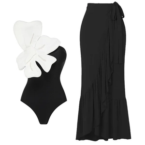 One-shoulder black swimsuit set with 3D white flower and matching ruffled maxi skirt