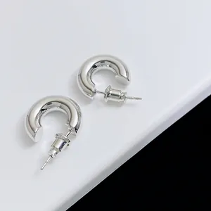 Close-up of polished silver C-hoop earrings with butterfly backings on a white stand