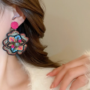 Detail of bohemian floral embroidered earring with colorful beads and crystal on model