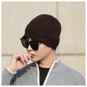 Detail of dark brown ribbed knit beanie with branded label and thermal winter texture
