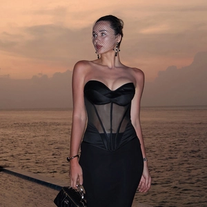 Elegante top a corsetto nero con mesh trasparente e stecche, mostrato in riva al mare